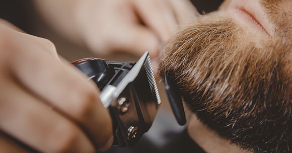 Barbero recortando barba a un cliente